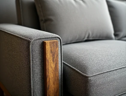 Szara sofa tapicerowana z drewnianym wykończeniem podłokietnika